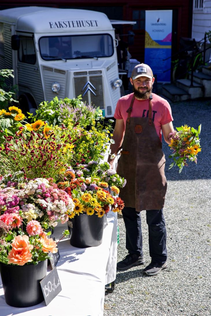 Markedssalg gir god synlighet og kundekontakt, og har vært viktig for å markedsføre snittblomstproduksjonen. Foto: Undeland gard. Mann med blomster i forgrunnen og en kassebil i bakgrunnen